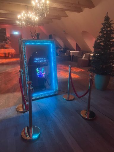 Fotobox Winterhochzeit Neonbeleuchteter Spiegel mit Absperrbändern in festlich dekoriertem Raum.
