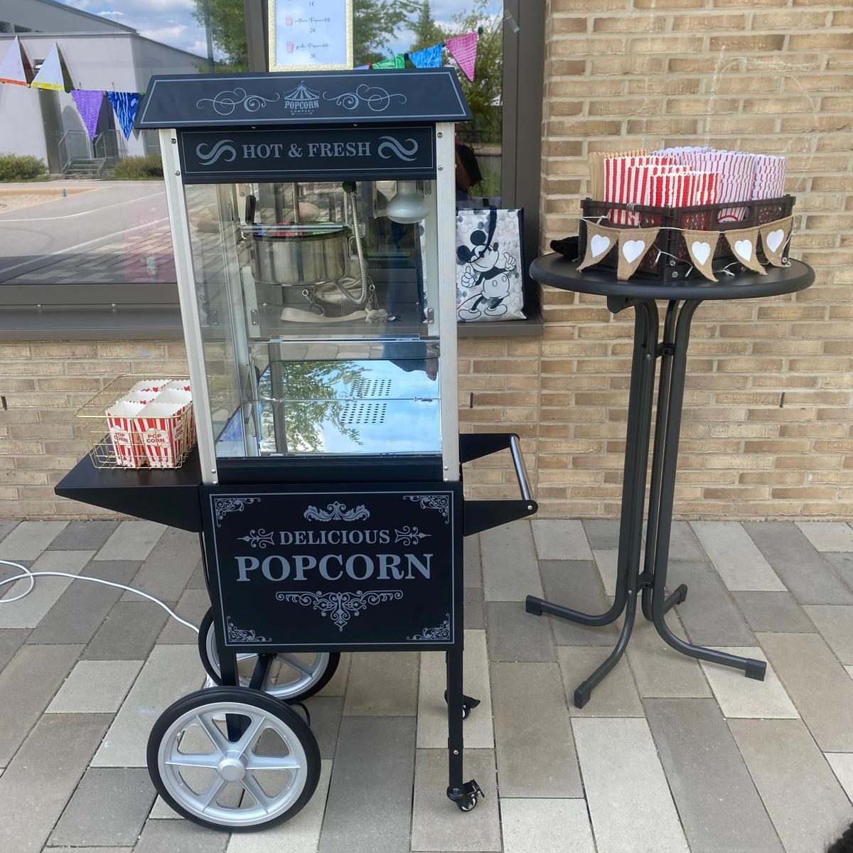Popcornmaschine Popcornmaschine mit Schalen und Popcorntüten neben einem Tisch.